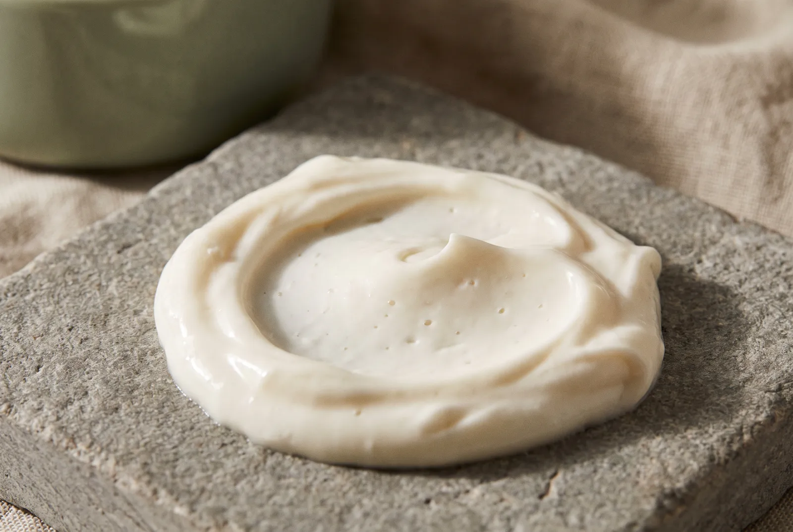 Porción de crema blanca y espesa, con el borde en remolino, sobre una piedra gris vista muy de cerca