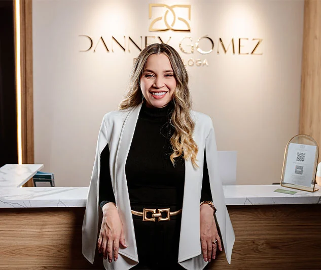 Dra. Danney Gómez en la recepción del consultorio, con el logo en la pared.